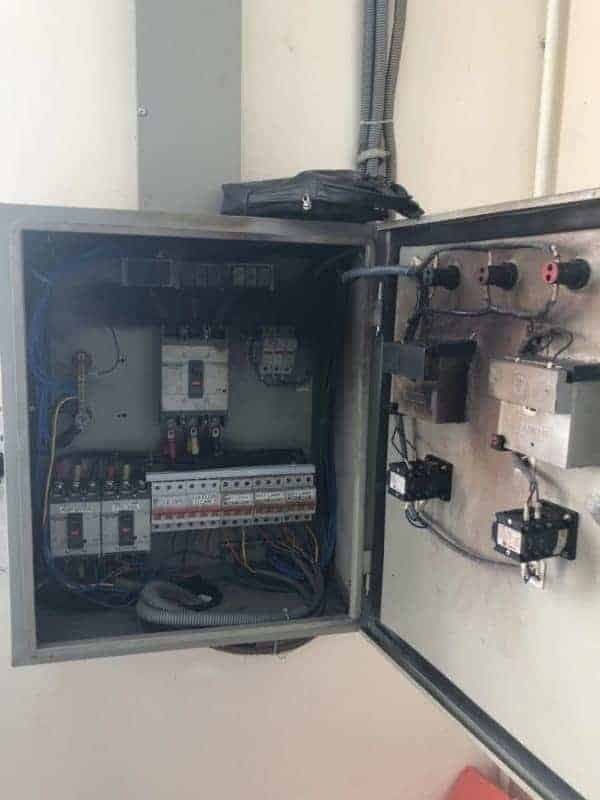 Thợ điện đang kiểm tra và siết lại các đầu nối của aptomat để đảm bảo an toàn.