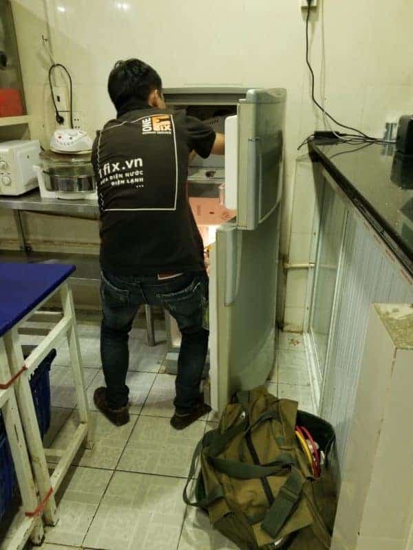Thợ 1Fix đang kiểm tra hệ thống điện phức tạp phía sau tủ lạnh để tìm nguyên nhân chập cháy.