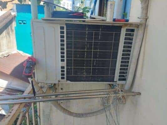 Cục nóng điều hòa được lắp đặt chắc chắn trên giá đỡ chữ L bên ngoài tường nhà.