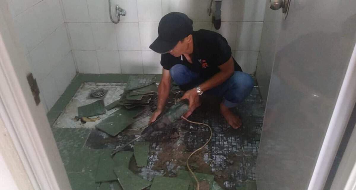 Thợ thi công đang đục phá lớp bê tông cũ xung quanh hộp kỹ thuật để chuẩn bị cho việc chống thấm.