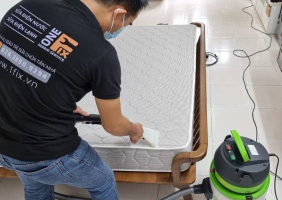 Kỹ thuật viên đang hút bụi bề mặt nệm lò xo.