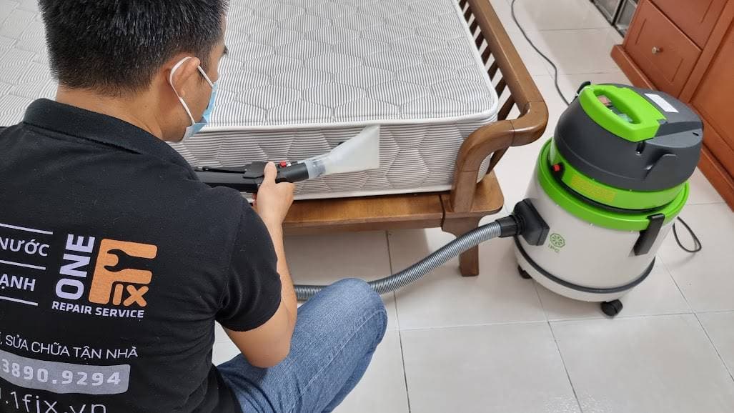 Thợ 1Fix sử dụng máy hút bụi công suất lớn để làm sạch bề mặt nệm tại nhà khách hàng ở Quận 5.