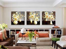 Một bộ ba bức tranh được bố trí cân đối phía trên ghế sofa phòng khách, tuân thủ quy tắc 2/3.