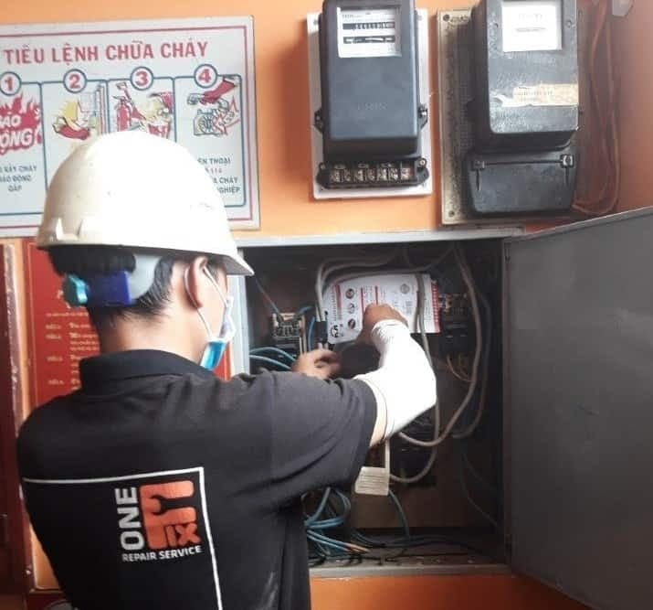 Một người đang kiểm tra chỉ số trên công tơ điện để tính toán tiền điện.