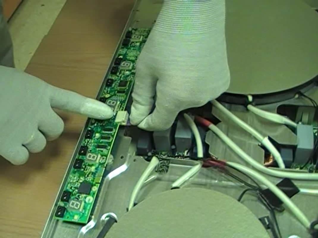 Thợ kỹ thuật đang kiểm tra và sửa chữa các linh kiện bên trong một chiếc bếp từ bị hỏng.