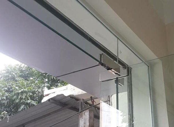 Thợ đang dùng lục giác để siết lại ốc kẹp kính cường lực bị xệ