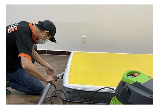 Thợ 1Fix sử dụng máy hút chuyên dụng để làm sạch sâu bề mặt nệm tại nhà khách hàng ở quận Bình Thạnh.