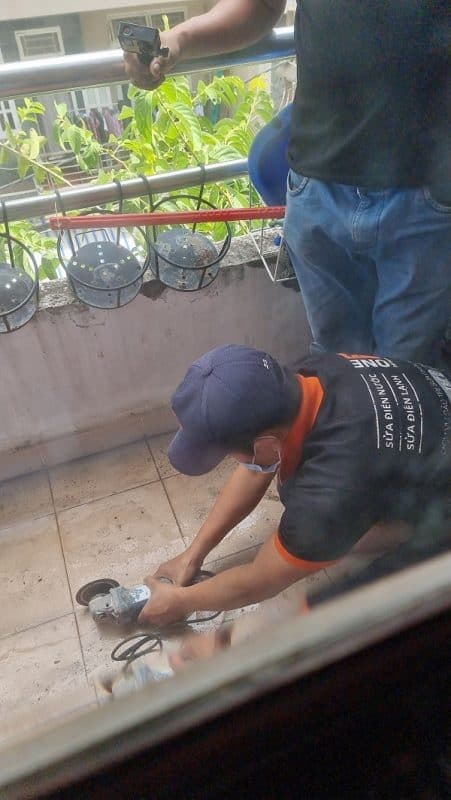 Một người thợ đang thi công lát gạch thẻ trên nền sân đã được cán phẳng.