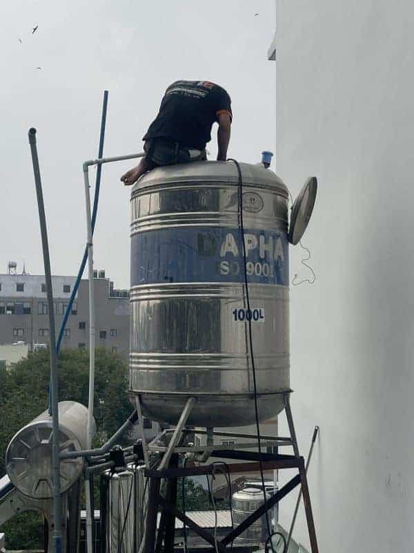 Thợ 1Fix đang kiểm tra hệ thống đường ống nước từ bồn chứa để tìm nguyên nhân rò rỉ hoặc tắc nghẽn.