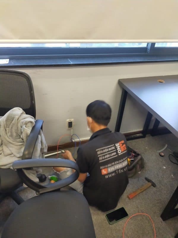 Thợ điện dùng đồng hồ vạn năng để kiểm tra điện áp tại ổ cắm trong nhà.