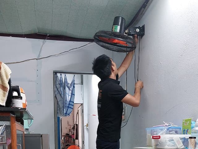 Thợ điện nước đang chuẩn bị dụng cụ và đánh dấu vị trí khoan tường.