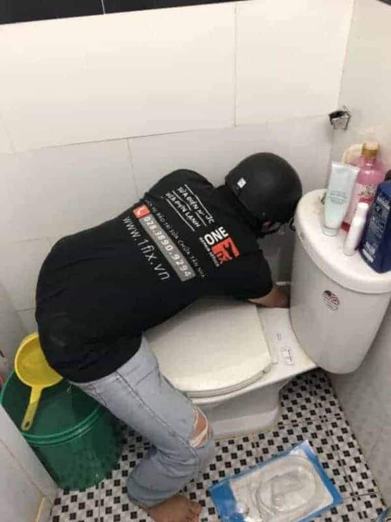 Bên trong két nước bồn cầu với cơ cấu phao và van xả.