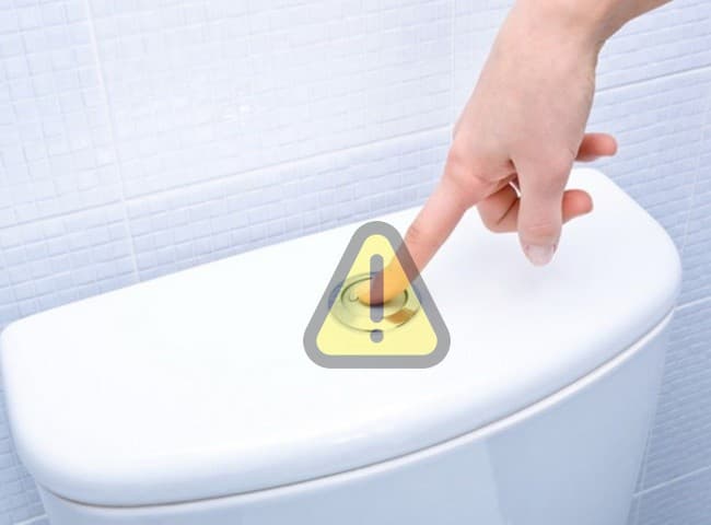 Cận cảnh nút nhấn xả nước bồn cầu bị kẹt do sử dụng lâu ngày và tích tụ cặn bẩn.