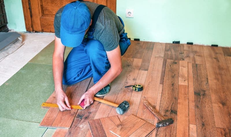 Thợ đang đo đạc và tính toán chi phí thi công sàn gỗ công nghiệp.