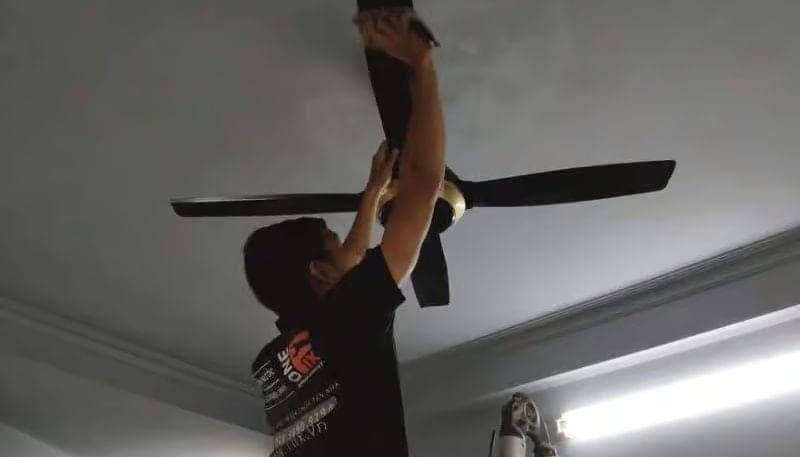 Thợ kỹ thuật đang kiểm tra động cơ quạt trần bị mất cân bằng gây rung lắc.