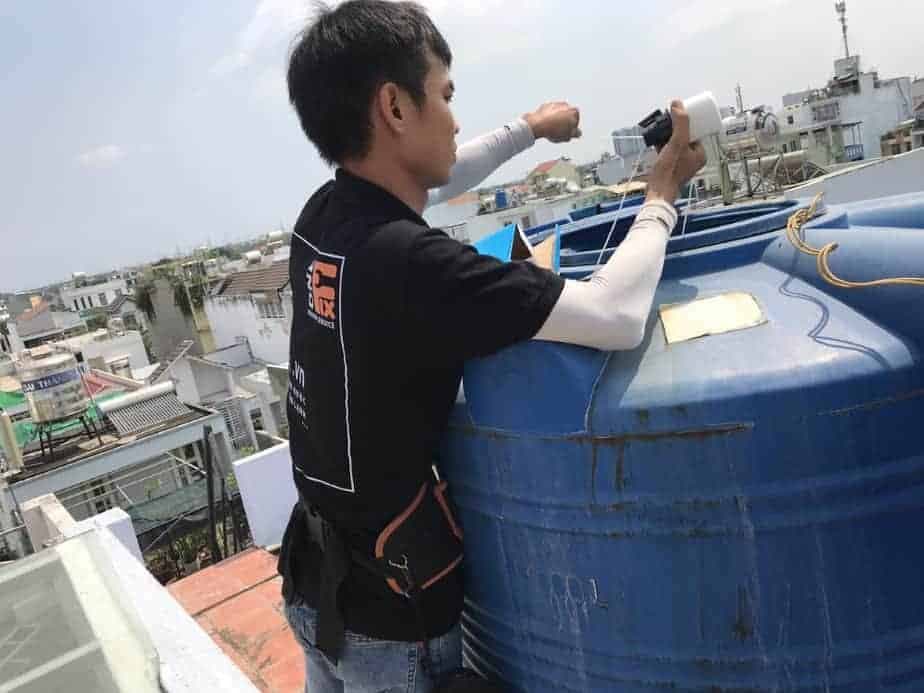 Thợ 1Fix đang thực hiện lắp phao điện chống tràn cho bồn nước một cách chuyên nghiệp và an toàn.