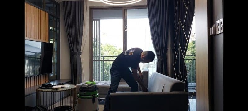 Thợ 1Fix đang sử dụng máy chuyên dụng để giặt ghế sofa tại một căn hộ ở Quận 10