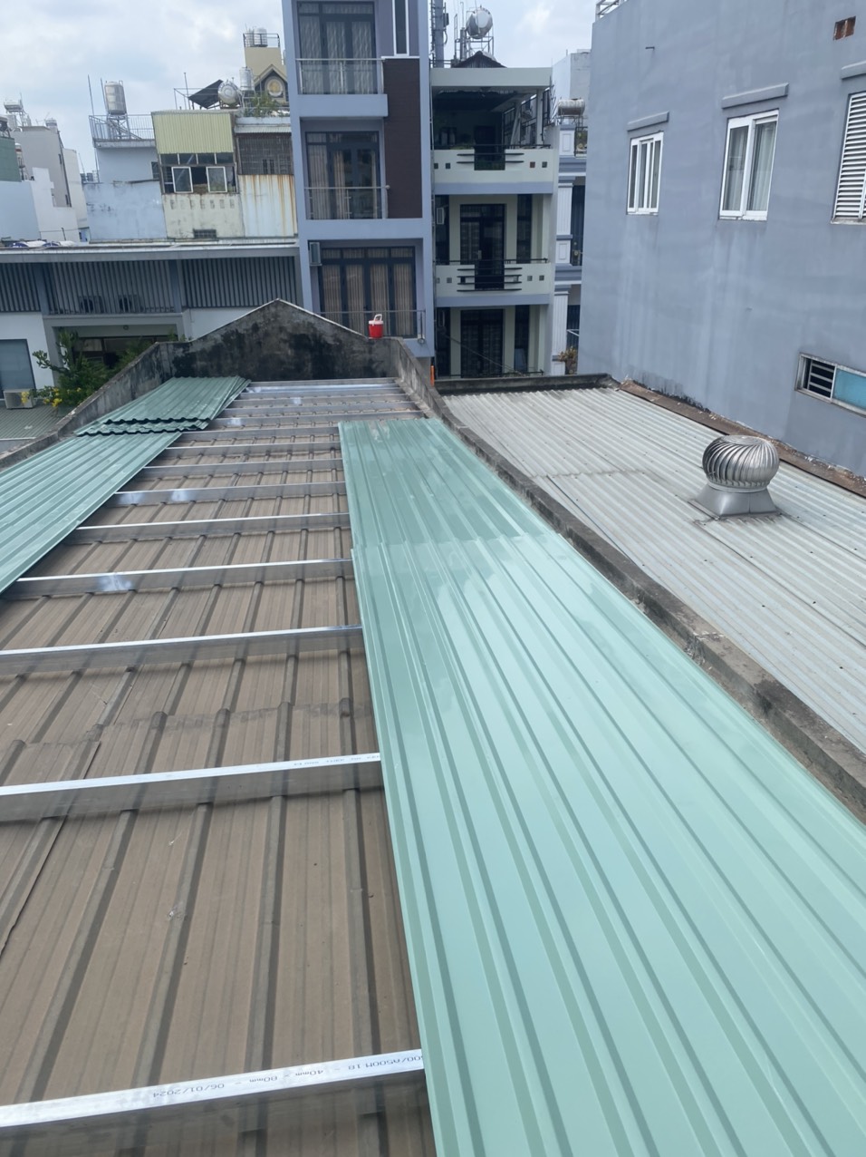 Mái tôn sau khi thi công — tôn lạnh mới màu xanh, khung sắt chắc chắn, có quả cầu thông gió inox